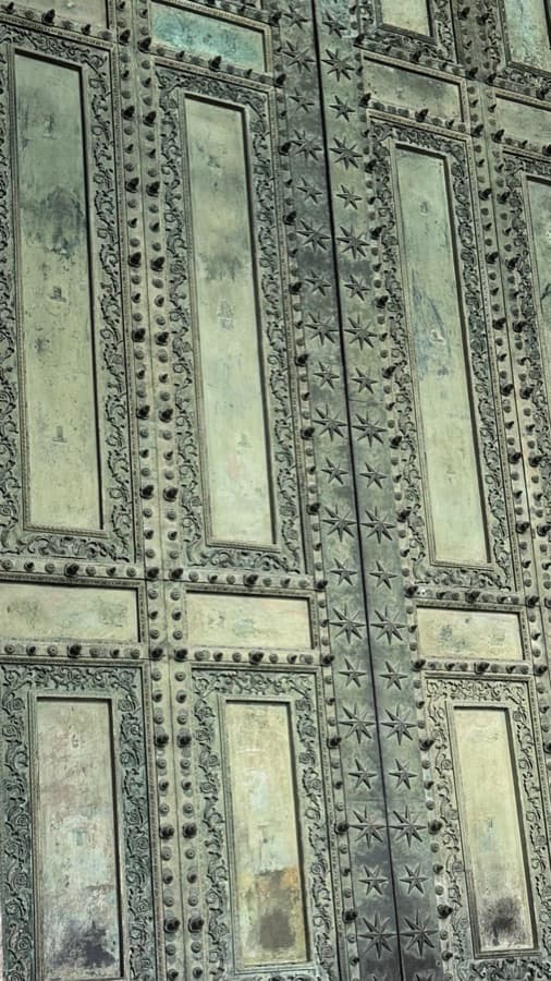 Weathered green door panels edged with rows of studs