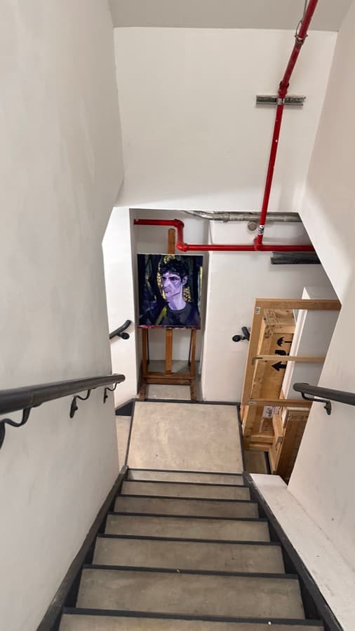 A white stairwell with red pipes running along the ceiling
