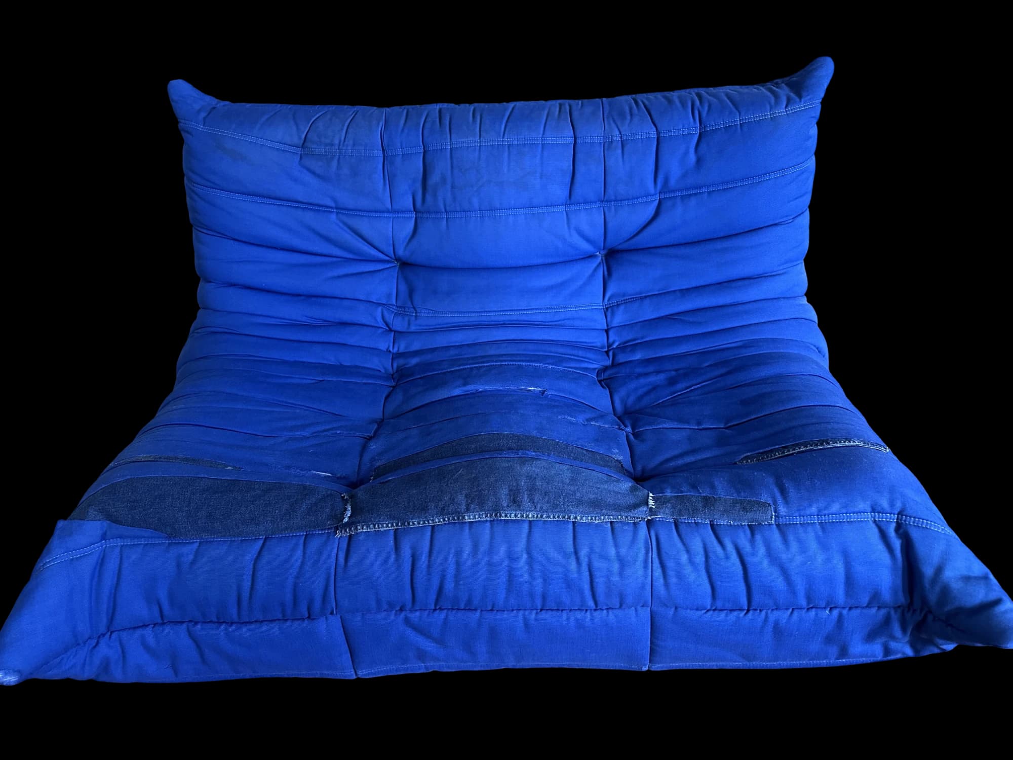 A blue Togo sofa with worn seams patched in old denim